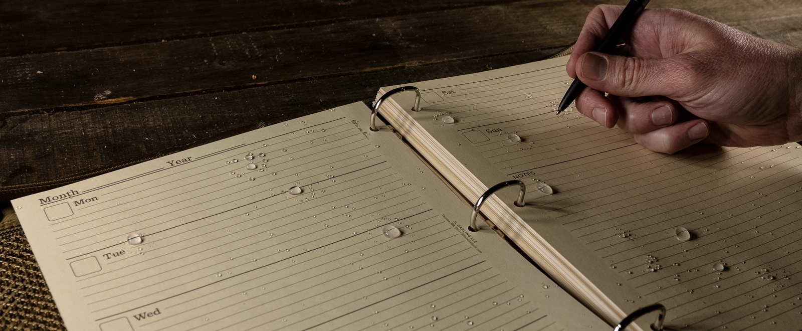 person writing in planner filled with wet large loose leaf pages