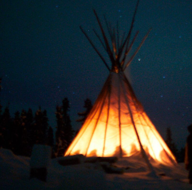 Teepee lit up at night with a silhouette of the retreat's participants.